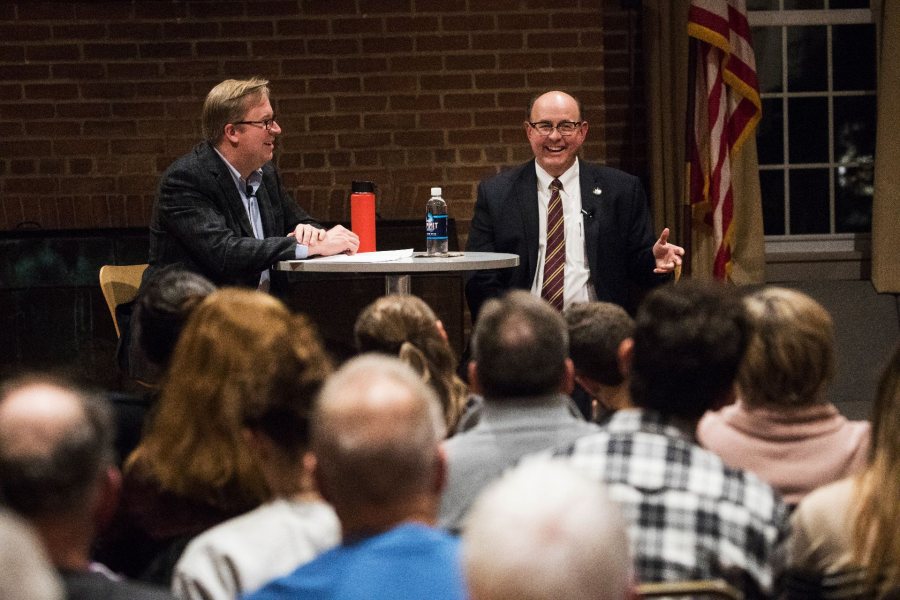 two wll dressed men giving a talk in front of a crowd